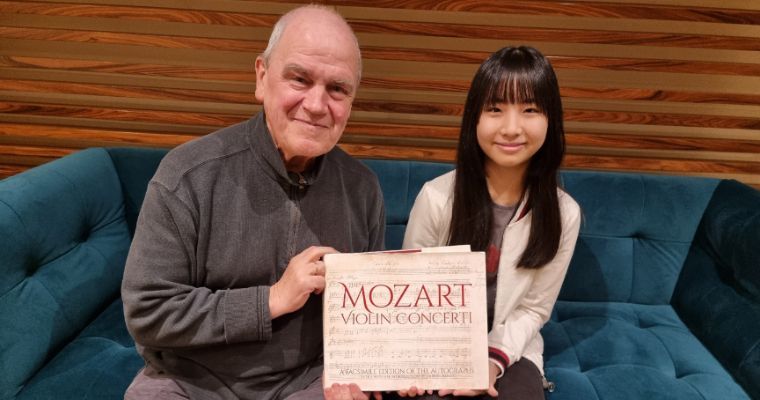 Hans Graf gifting an edition of Mozart's Violin Concerti to Chloe Chua &copy; Singapore Symphony