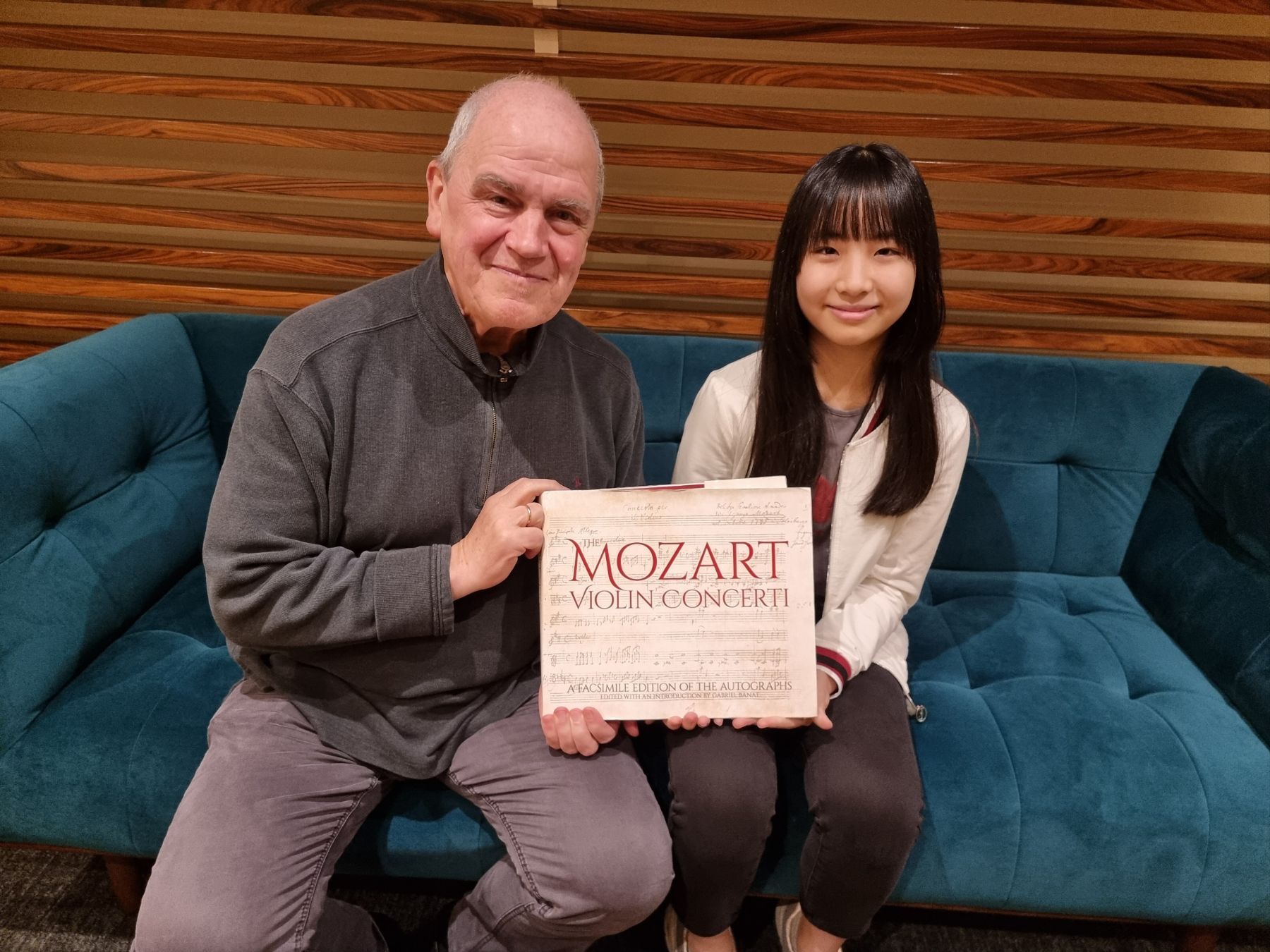 Hans Graf gifting an edition of Mozart's Violin Concerti to Chloe Chua &copy; Singapore Symphony
