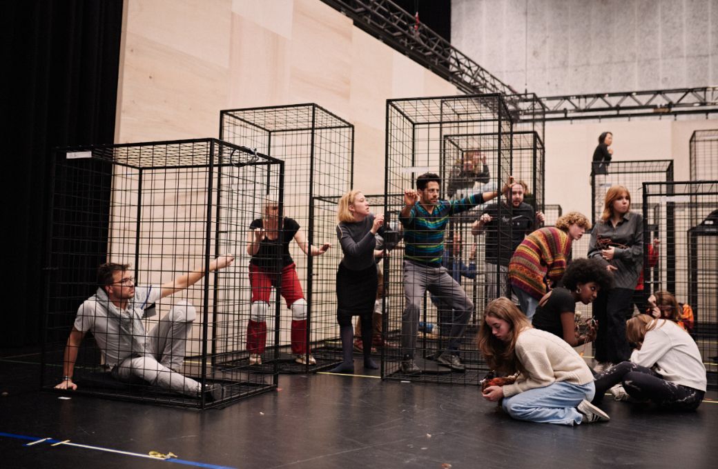 Cast and chorus rehearsing in cages &copy; Milagro Elstak
