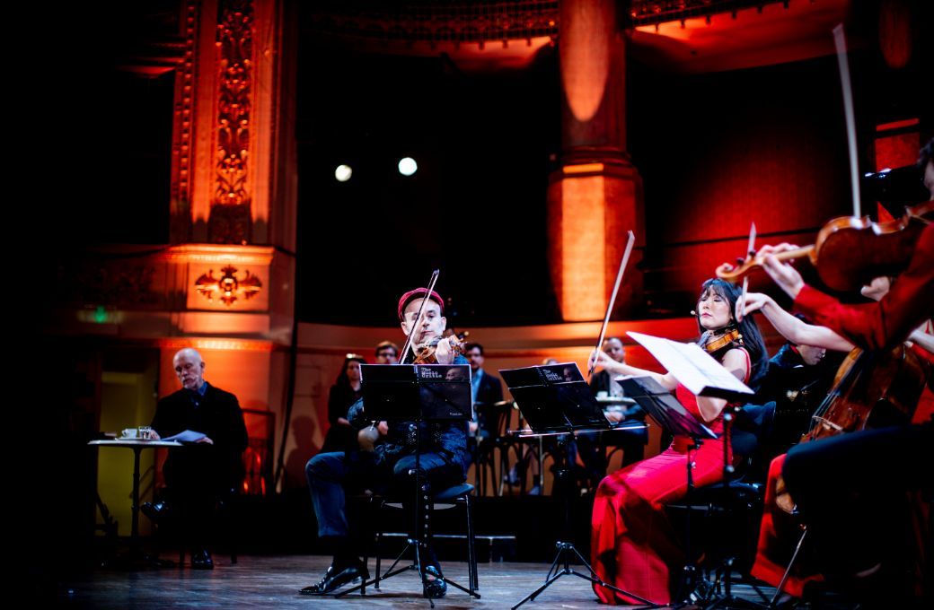 Alexey Igudesman leads musicians, while Malkovich looks on © Julia Wesely